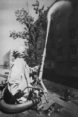 [Worker washing down a contaminated building with special chemicals]
